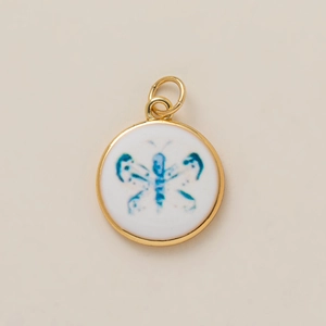 Detailed close-up of a round gold-plated pendant featuring a blue watercolor butterfly design