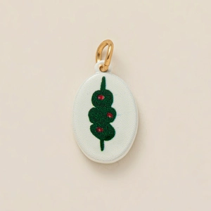 Close-up of ceramic oval pendant with green and red floral print and gold metal loop