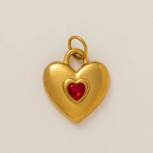Close-up of heart-shaped gold-plated pendant with a vibrant red stone inlay