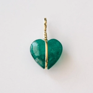 Macro-opname van een groene hartvormige hanger omwikkeld met goudkleurige metaaldraad