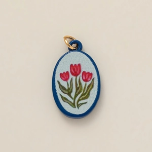 Macro shot of oval ceramic pendant with hand-painted red tulips and blue border