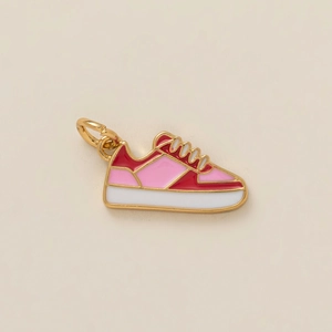 Detailed macro view of pink and red enamel sneaker pendant with golden metal edges