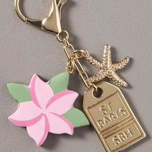 Detail of pink flower, golden starfish, and ST BARTS engraved charm on a luxury keychain
