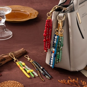 Bohemian beaded keychain pendant with colorful resin stones on a grey handbag