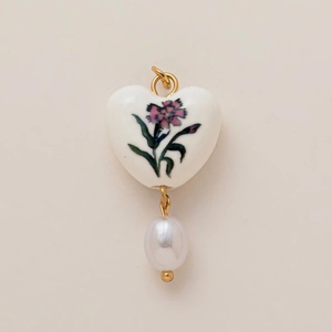 Dettaglio del ciondolo a cuore in ceramica vintage con fiori e perla a goccia