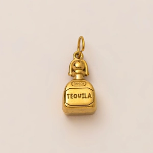 Macro detail of a 18K gold plated tequila bottle pendant with engraved text