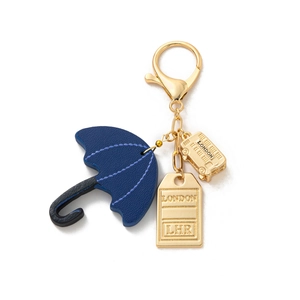 Detailed close-up of a London travel keychain with blue leather umbrella and golden bus charm