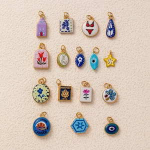 Pendentifs variés en acier titane et émail avec motifs d'étoiles, tulipes et passeports