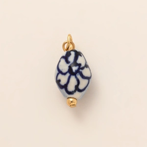 Macro view of blue and white floral ceramic bead pendant with 18K gold-plated fittings