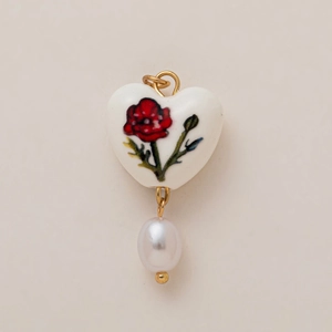 Macro di ciondolo a cuore in ceramica con fiori rossi e perla bianca sul fondo