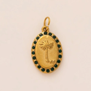 Macro détaillée d'un pendentif ovale doré avec relief palmier et pierres de zircon vert