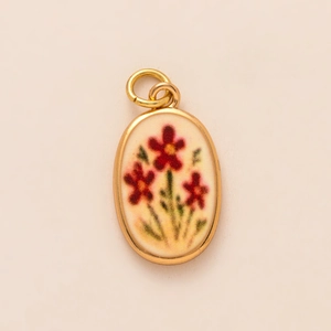 Primer plano de un colgante ovalado bañado en oro con esmalte de flores rojas y aire retro