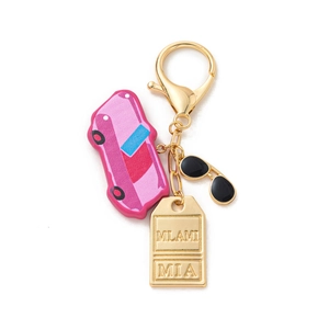 Detail of gold keychain with Miami tag, pink vintage car charm and sunglasses