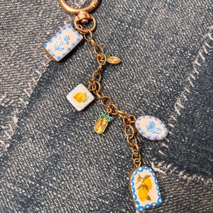 Gros plan du porte-clés doré avec pendentifs fruits et fleurs sur tissu denim