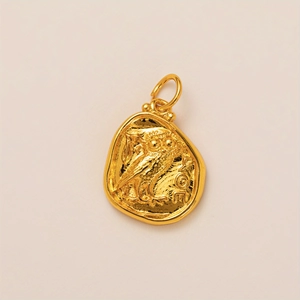 Macro detail of a 14K gold plated owl coin pendant with vintage textured finish