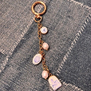 Détail d'un porte-clés doré avec breloques florales bleues et perles de nacre