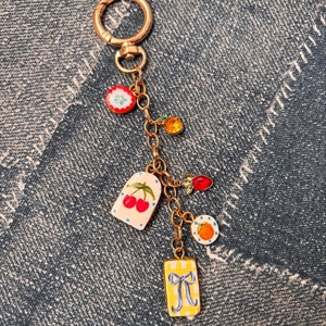 Détail de pendentifs de fruits colorés et de nœuds sur un porte-clés doré pour sacs