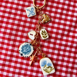 Vue détaillée d'un porte-clés doré avec charms bleus et pendentif cœur sur fond à carreaux
