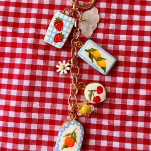 Détails de breloques fruitées colorées avec fraise et citron sur chaîne dorée