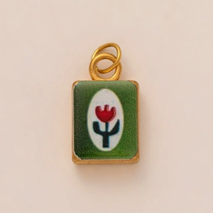 Detailed macro of vintage rectangular 18k gold pendant with red tulip and green enamel