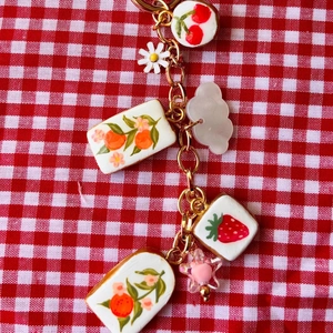 Détails de pendentifs de fruits colorés et de charmes floraux sur un porte-clés doré