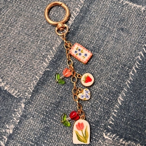 Gros plan de pendentifs en émail coloré avec fleurs et fruits sur un porte-clés doré