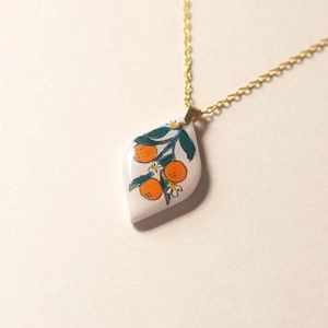 Macro shot of stainless steel teardrop pendant with hand-painted orange fruit pattern