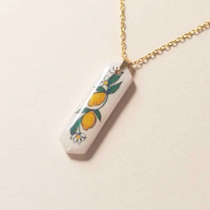 Close-up of 18K gold-plated necklace featuring a floral lemon pattern on a ceramic pendant
