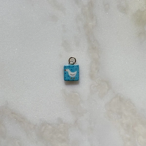 Detalle del colgante azul con patrón de ganso blanco sobre mármol claro
