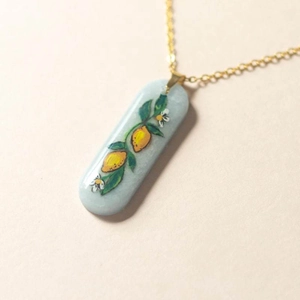 Detail of 18K gold plated lemon pattern pendant necklace with light blue glaze