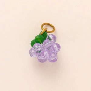 Detailansicht eines lila Traubenanhängers mit grünen Blättern und goldenem Ring