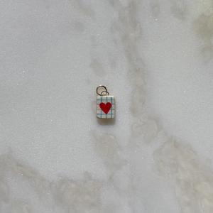 Detalle del colgante rectangular a cuadros azul claro con corazón rojo y aro dorado