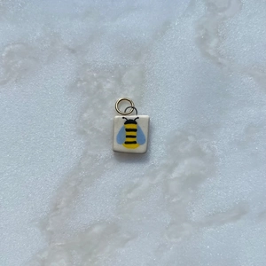 Detalle de colgante cuadrado de abeja con esmalte amarillo y negro y aro dorado