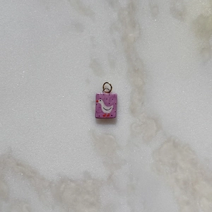 Primer plano de colgante rectangular morado con diseño de ganso y aro dorado metálico