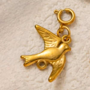 Vue macro d'un pendentif oiseau doré montrant les ailes et le fermoir à ressort