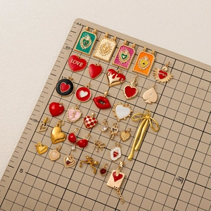Sélection de breloques tarot en émail doré avec motifs cœur et nœud sur tapis quadrillé