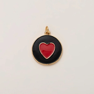Vue détaillée d'un pendentif rond noir avec cœur rouge et bordure dorée perlée