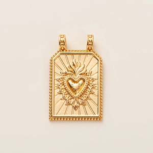 Détail macro du pendentif rectangulaire plaqué or avec un cœur sacré vintage gaufré