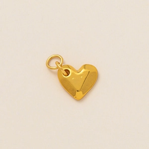 Détail d'un pendentif coeur doré avec surface facettée en 3D et anneau en métal ouvert