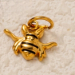 Détail macro d'un pendentif abeille plaqué or 18 carats avec rayures noires et anneau