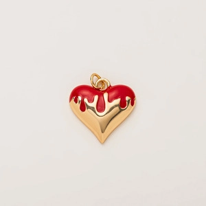 Détail du pendentif en cœur avec effet émail rouge dégoulinant et finition dorée polie