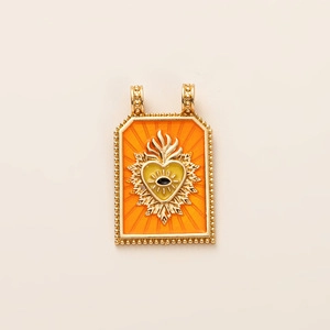 Détail d'un pendentif rectangulaire sacré-cœur plaqué or avec émail orange et œil protecteur