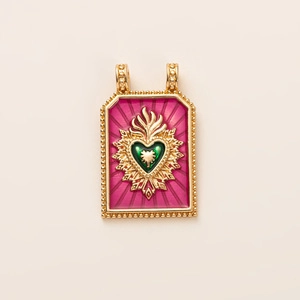 Vue détaillée du pendentif Sacré-Cœur vintage en émail avec placage d'or et fond rouge rayonné