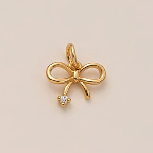 Gros plan d'un pendentif nœud doré avec pampille sertie d'un diamant étincelant
