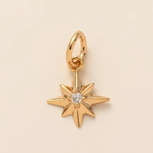 Détail d'un pendentif étoile à huit branches en or serti d'une pierre de cristal blanc