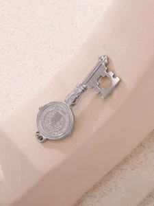 Dettaglio di un ciondolo a chiave vintage in argento con rilievo e croce traforata