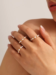Set di tre anelli eleganti con perle dorate e perle di riso bianche sulle dita