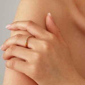 Minimalistische PVD gouden golfring met pavé kristallen gedragen op de hand van model