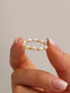 Dettaglio macro di un elegante anello di perle e sfere d'oro con texture lucide