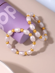 Dettaglio di anelli con perline bianche e distanziatori dorati su supporti color viola
